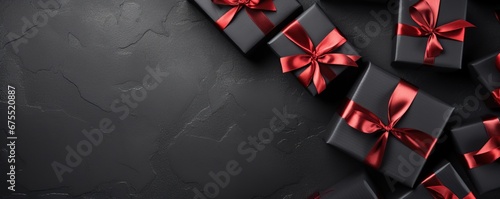 Black Friday. Top view of black christmas boxes with red ribbon on black and white paper background with copy space for text