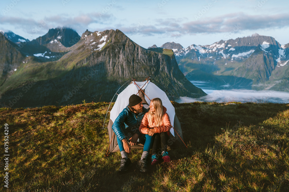Fototapeta premium Couple friends on romantic vacations hiking with camping tent gear traveling together, exploring mountains in Norway, they enjoy outdoor family activities and healthy lifestyle eco tourism