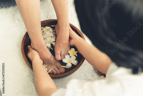 Woman indulges in blissful foot massage at luxurious spa salon while masseur give reflexology therapy in gentle day light ambiance resort or hotel foot spa. Quiescent