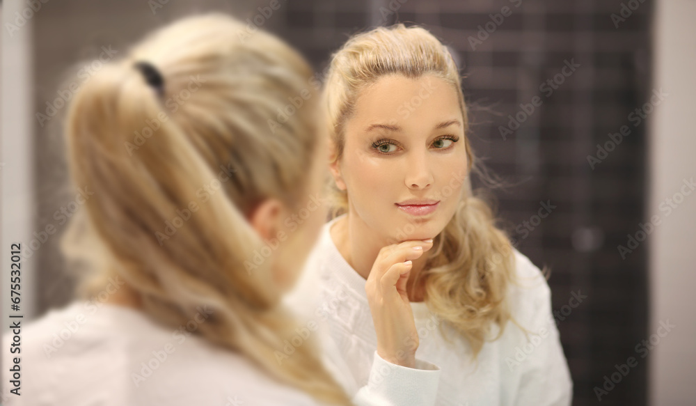 woman looking in the mirror in the bathroom and taking care of her skin. woman looking in the mirror in the bathroom and taking care of her skin.