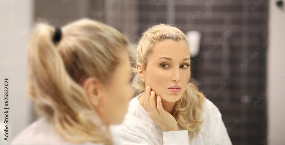 woman looking in the mirror in the bathroom and taking care of her skin. woman looking in the mirror in the bathroom and taking care of her skin.