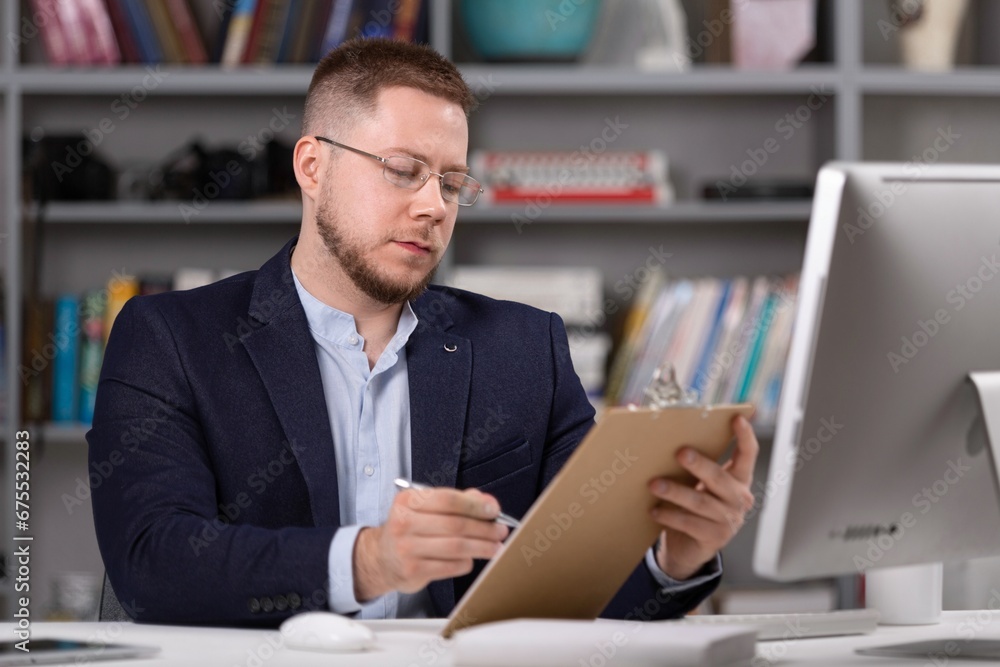 Male psychoanalyst with clipboard working on pc Male psychoanalyst with clipboard working on pc