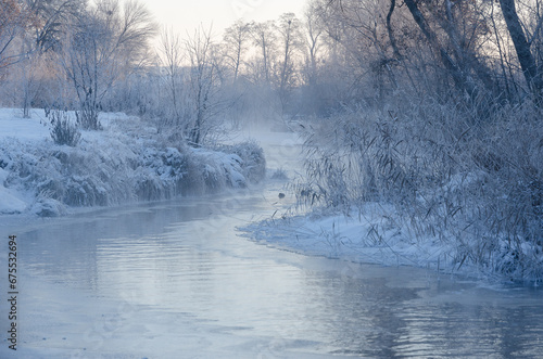 Dawn in winter on the river, fog over the water and frost.