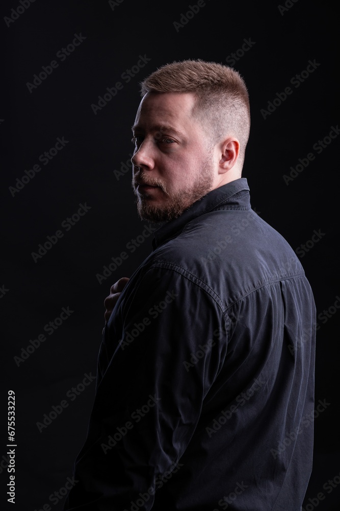 Strict and stylish Man in black shirt on dark background.