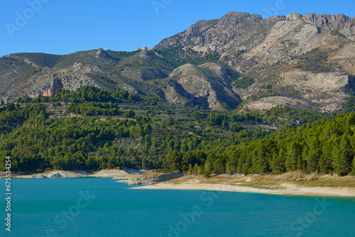 Guadalest reservoir surrounded by forest at the foot of the mountain, beautiful landscape with turquoise water. Guadalest, Valencia, Spain.