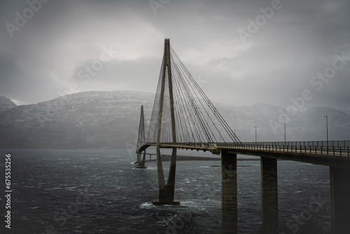 Dramatic evening panorama photo on Sandnessjoen bridge very windy twilight, late autumn, low level clouds over Vefsnfjord. View from the left side. Car travel by nordic roads to Norway photo