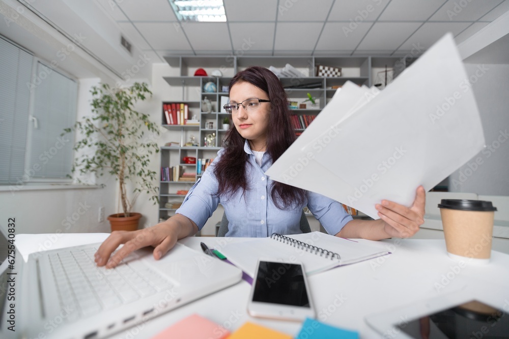 Young woman sitting at table and working with business paper Young woman sitting at table and working with business paper