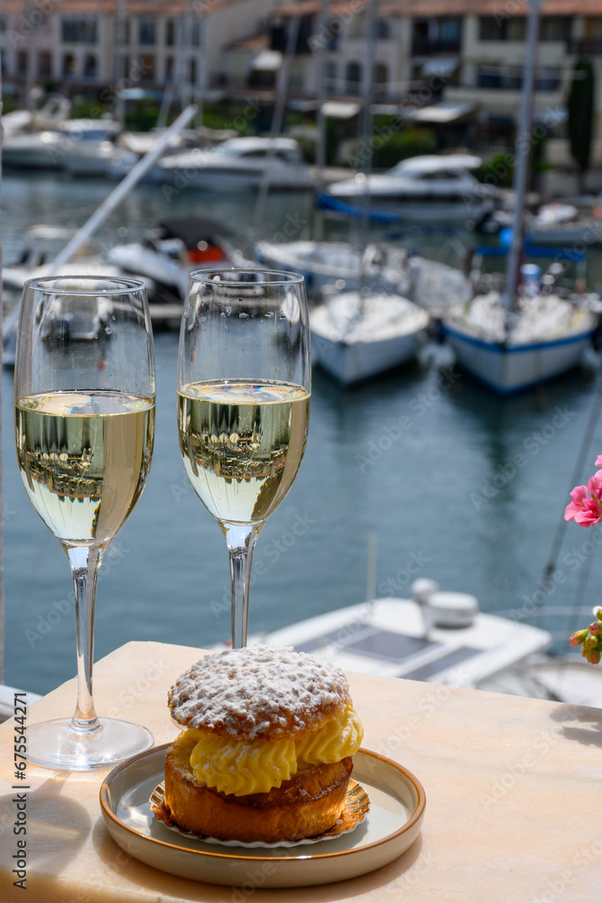 Drinking of French brut champagne sparkling wine with cake Tarte Tropezienne, club party in yacht harbour of Port Grimaud near Saint-Tropez, French Riviera vacation, France