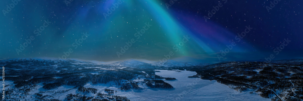 Very wide scenic aerial panorama on frozen lake, mountains with snow mobile traces, northern green lights over mountains. Scandinavian night winter landscape, Norway, Sweden