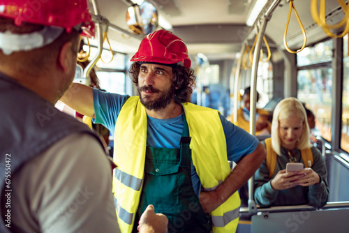 Male construction worker riding on the bus with colleague