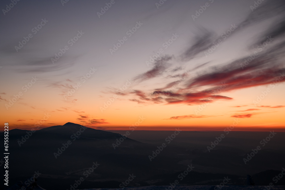 Fascinating colors of colorful winter sunset sky over distant silhouetted mountains