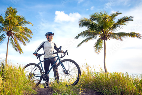 bearded male cyclist in yellow clothes on a bicycle against the background of palm trees in nature. sports, hobbies and entertainment for health
