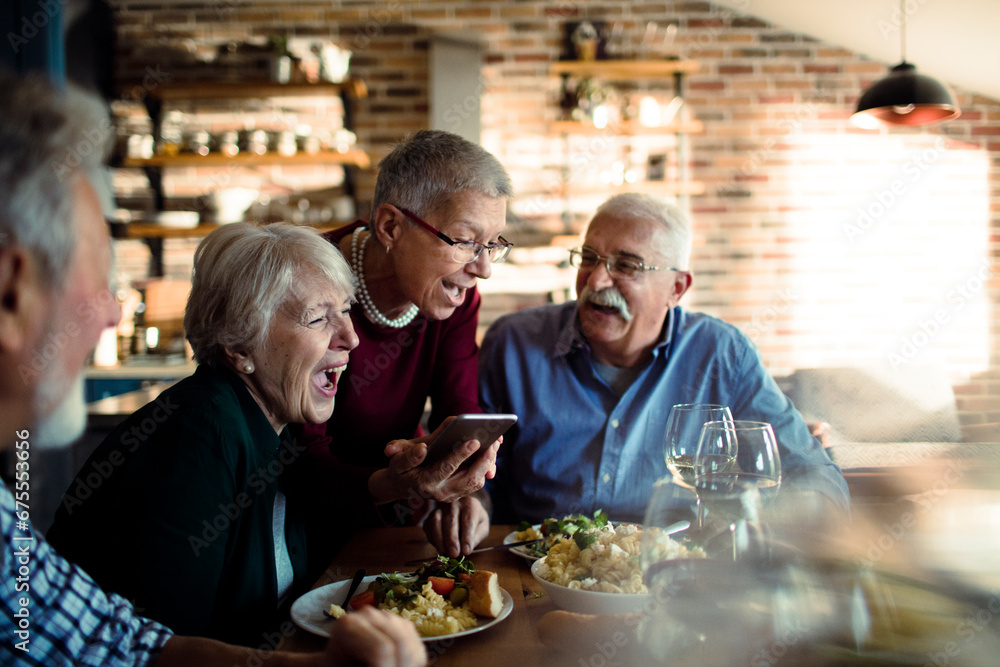 Senior friends laughing over dinner at home