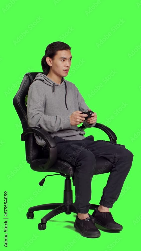 Side view of young gamer playing videogames over full body greenscreen template, using joystick and enjoying competition with people online. Person having fun with rpg action contest on console. Side view of young gamer playing videogames over full body greenscreen template, using joystick and enjoying competition with people online. Person having fun with rpg action contest on console.