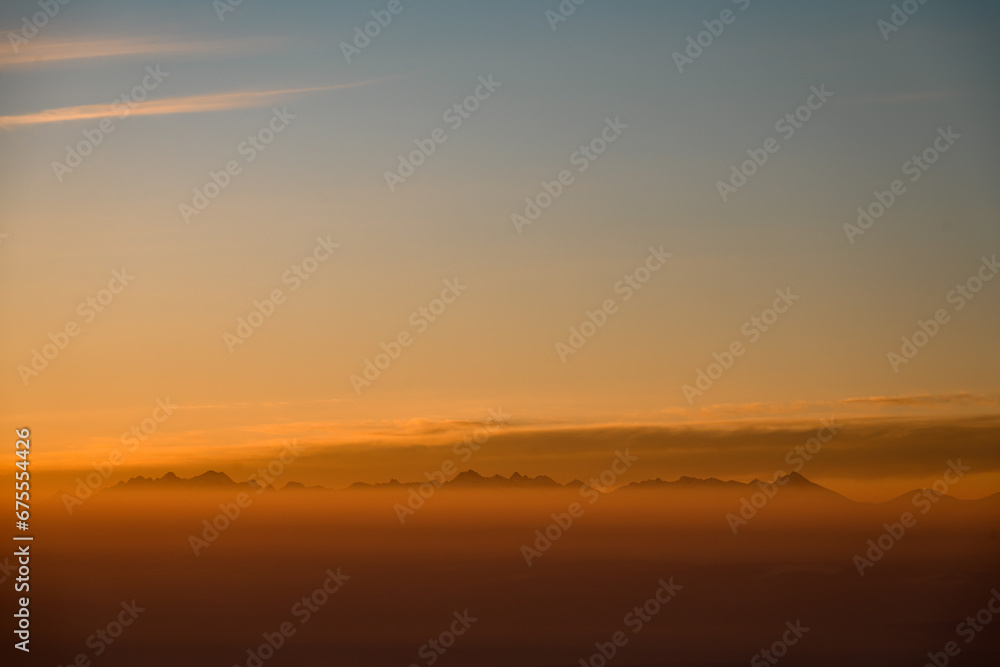 Aerial view on mountain peaks during sunset. High mountain landscape in winter.