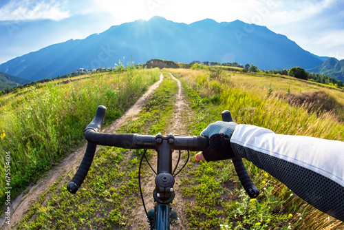 hands on the handlebars of a bicycle of a cyclist riding along a trail in nature. Point of view