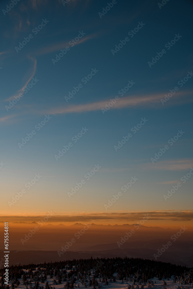 Beautiful aerial view on snow covered mountain peaks during sunset. High mountain landscape in winter.