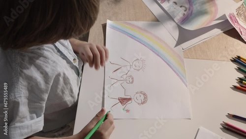 Young boy brings his family to life on paper through his drawing skills. The artwork portrays a cozy family idyll, child's creativity and imagination. Loving and joyful family. Divorce and children
