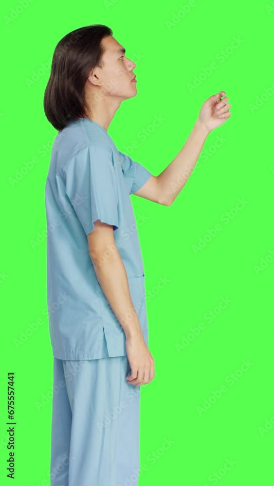 Profile of asian medical assistant sees hologram in studio with greenscreen layout, working with holographic image and artificial intelligence. Male nurse in uniform with healthcare expertise. Profile of asian medical assistant sees hologram in studio with greenscreen layout, working with holographic image and artificial intelligence. Male nurse in uniform with healthcare expertise.