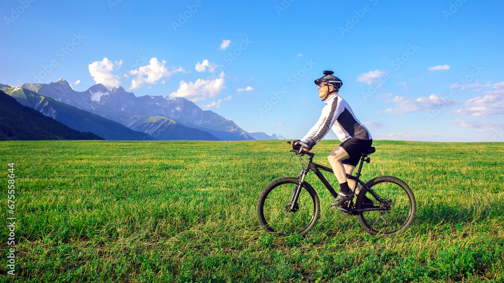 Obraz premium The cyclist rides a bicycle on the green grass on the field. Outdoor sports. Healthy lifestyle.