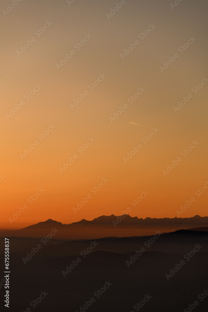 Beautiful view of winter landscape with hills and mountains silhouettes during sunset