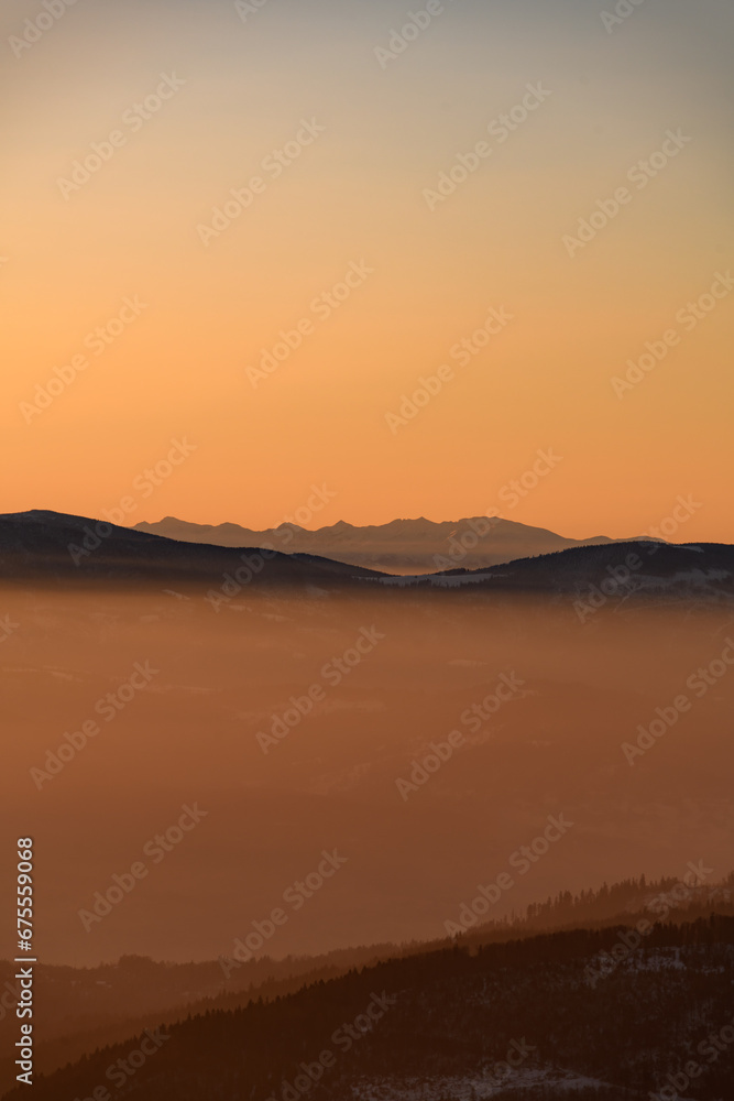 Amazing vertical view of winter landscape with hills and mountains silhouettes during sunrise