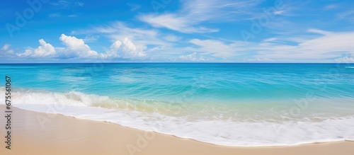 The breathtaking beauty of the beach during summer with its turquoise blue sea stunning landscape and golden sand is enhanced by the warm sunlight clear sky and fluffy clouds reflecting in 