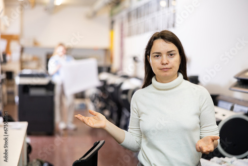 Portrait of positive woman printing office worker gesturing and looking at camera.