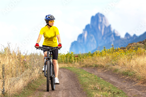 beautiful woman cyclist in a yellow shirt rides a bicycle along a field road. sports, hobbies and entertainment for health