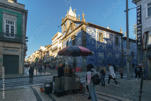 Chestnut food stand in front of Chapel of Souls or Capela das Almas with beautiful blue white azulejo tiles facade in Porto, Portugal