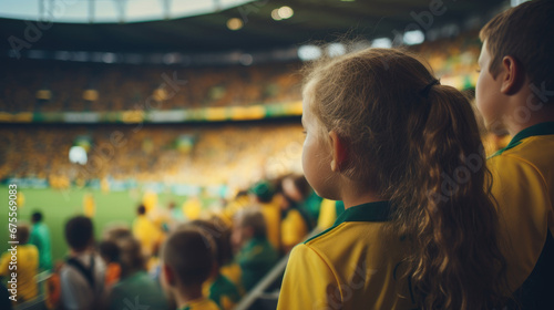 A young girl in yellow and green attire watches the Australian team at the Women s World Cup from the stadium  with a blurred background.