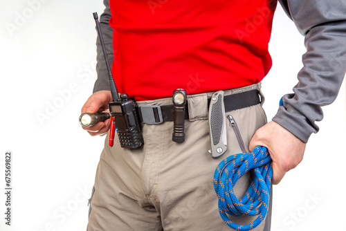 Pen, walkie-talkie, knife and flashlight with clips on the waistband of trekking pants. EDC items