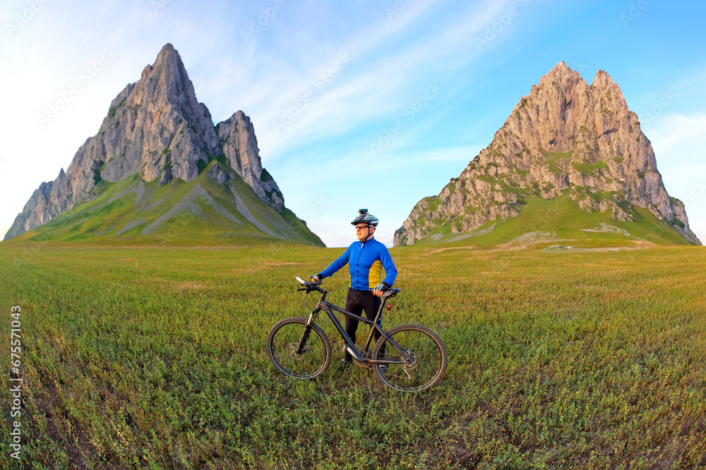 Fototapeta premium cyclist with a bicycle is resting on a green field against a blue sky. sports and recreation in nature