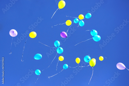 many multicolored balloons flying in the blue sky. Holiday accessories and decorations