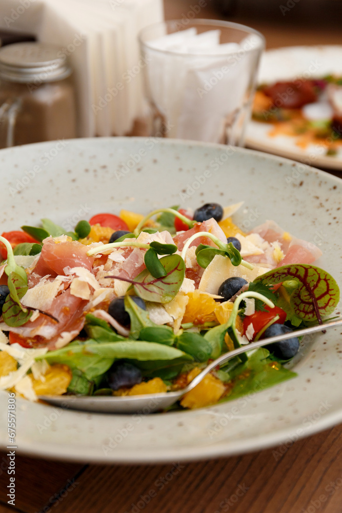 Salad with prosciutto, parmesan, berries in a restaurant, close-up. Healthy eating. Salad with prosciutto, parmesan, berries in a restaurant, close-up. Healthy eating.