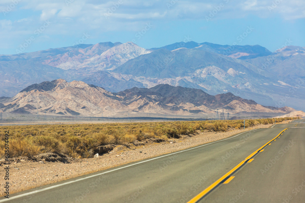 View of Mojave Desert national reserve landscape, an arid rain-shadow desert, California, United States of America, summer sunny day with road, mountains, sand dunes and a blue sky