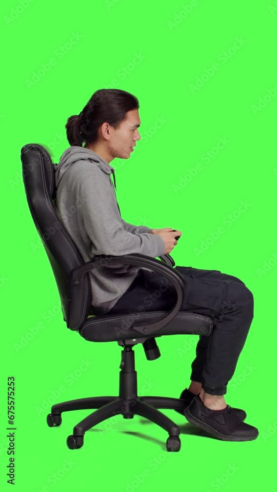 Profile of player enjoys roleplaying battle against greenscreen backdrop while playing online games with controller. Asian guy delights in web video games, gaming enthusiast with excellent focus. Profile of player enjoys roleplaying battle against greenscreen backdrop while playing online games with controller. Asian guy delights in web video games, gaming enthusiast with excellent focus.