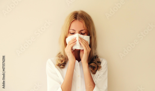 Sick exhausted caucasian young woman employee sneezing blow nose using tissue at home photo