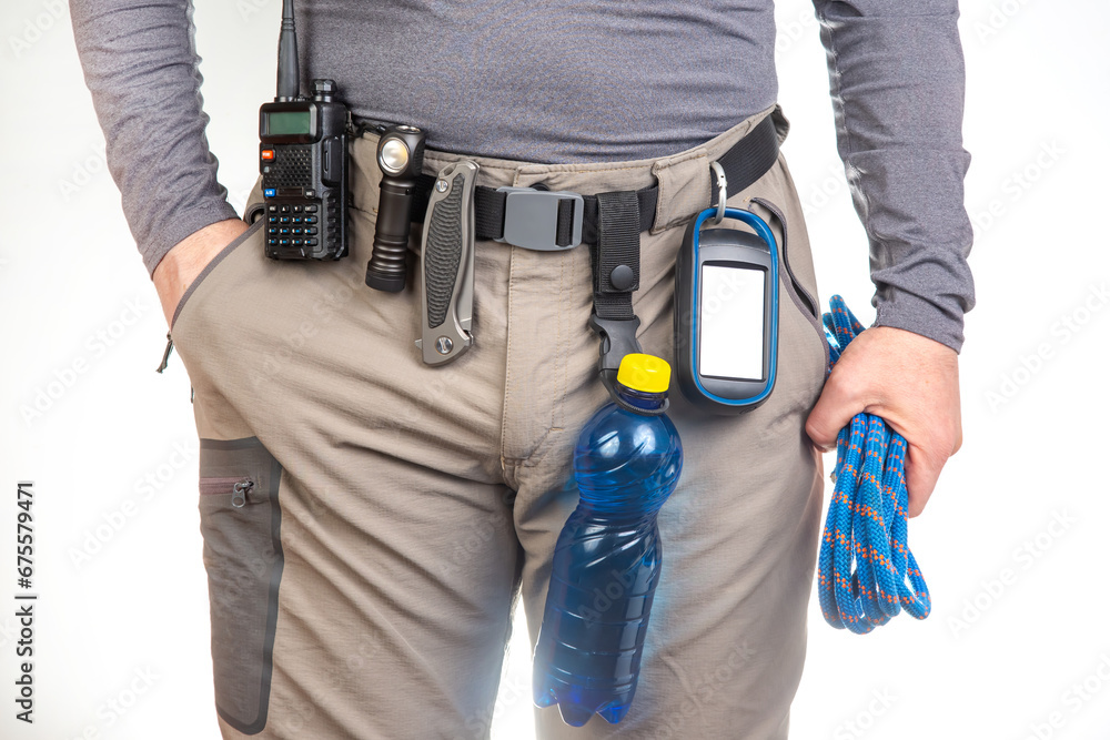 water, walkie-talkie, flashlight, knife, GPS navigator, climbing rope on the belt of the tourist trekking pants. equipment for tourism and travel. EDC items water, walkie-talkie, flashlight, knife, GPS navigator, climbing rope on the belt of the tourist trekking pants. equipment for tourism and travel. EDC items