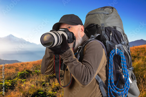 bearded man tourist photographer with a backpack photographs the beauty of nature in the mountains. nature hikes in the mountains © photosaint