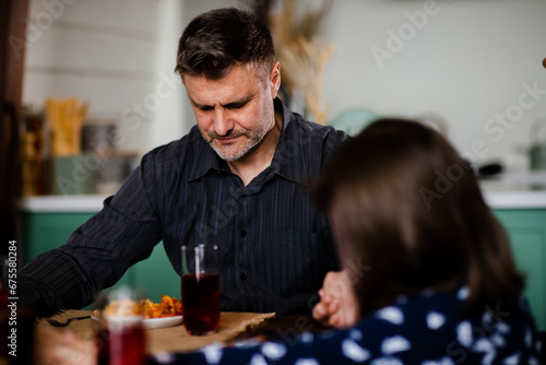 Adult man praying before food with family at the dining table. Jewish parent blessed during having a meal. Religious holiday. Spiritual union with god. Lunch thanksgiving