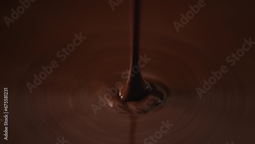 Slow motion shot pouring melted chocolate, close-up seamless dripping hot liquid chocolate flows, waves flowing molten chocolate or dark caramel sauce. Chocolate wavy drip. Confectionery cooking photo