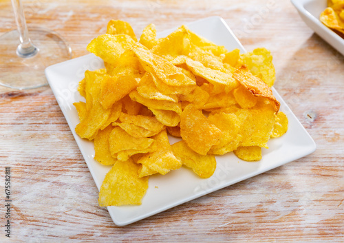 Plate of crispy deep-fried chips of thinly sliced natural potatoes. Popular vegetable snack..