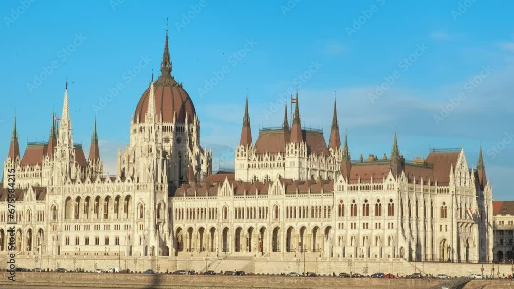 Budapest parliament over blue sunny sky. A view of Danube river bank against sunny facade of Budapest parliament. A concept of holiday in Budapest.