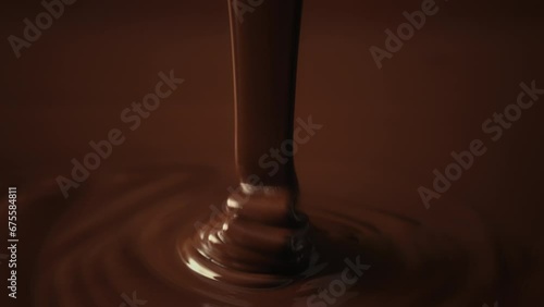 Slow motion shot pouring melted chocolate, close-up seamless dripping hot liquid chocolate flows, waves flowing molten chocolate or dark caramel sauce. Chocolate wavy drip. Confectionery cooking