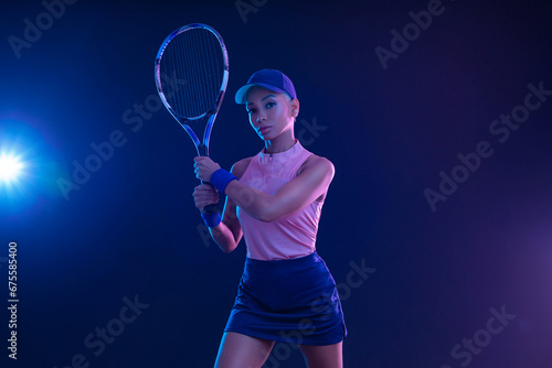 Tennis player woman with racket on tournament. Girl athlete with tenis racket on court with neon colors. Sport concept. Download a high quality photo for design of a sports app or tour events. © Mike Orlov