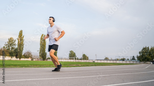 adult caucasian man jogging on the running track male athlete in stadium training run in sunny spring or summer day real people healthy lifestyle concept