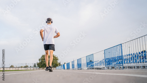 Fototapeta Naklejka Na Ścianę i Meble -  adult caucasian man jogging on the running track male athlete in stadium training run in sunny spring or summer day real people healthy lifestyle concept