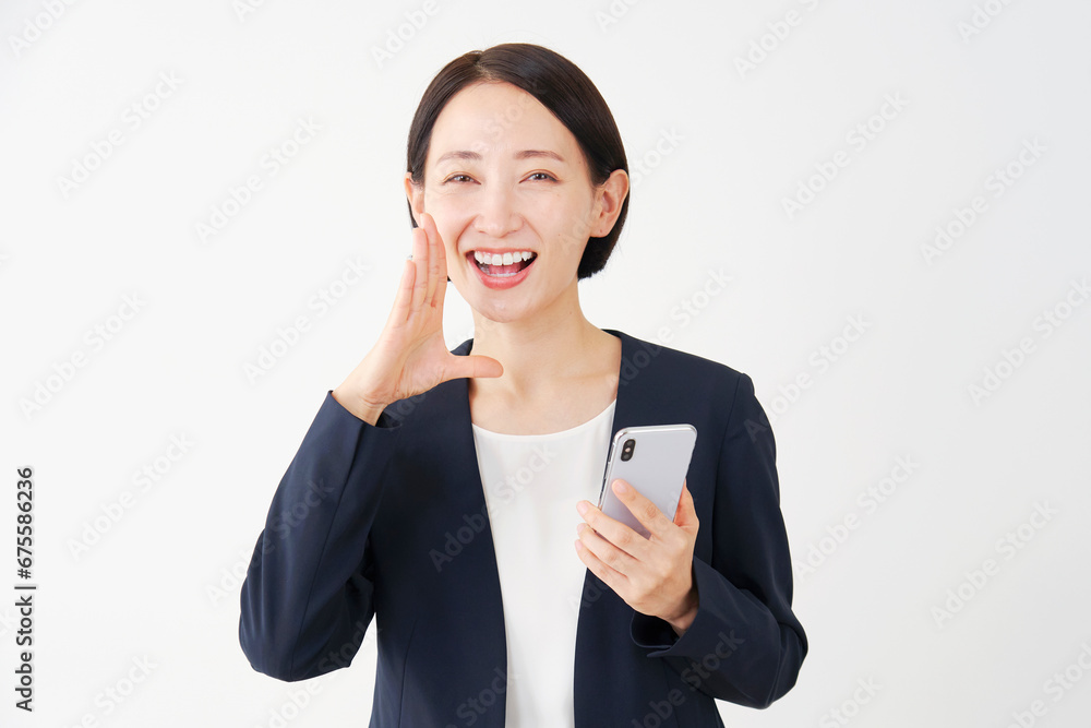 スマートフォンを持って呼びかける中年のビジネスウーマン 白背景 スマートフォンを持って呼びかける中年のビジネスウーマン 白背景