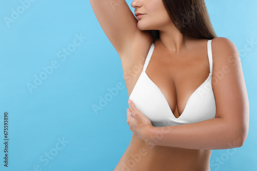 Woman with beautiful breast on light blue background, closeup. Space for text